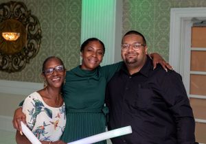 Small group of party guests socializing and posing together at an indoor celebration.