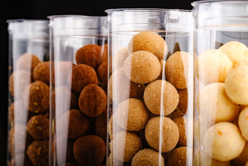 Four transparent cylindrical containers filled with assorted chocolate and sugar-dusted truffle balls.