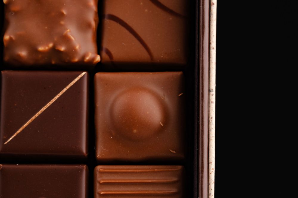Close-up of assorted dark and milk chocolate pralines in a luxury chocolate box.