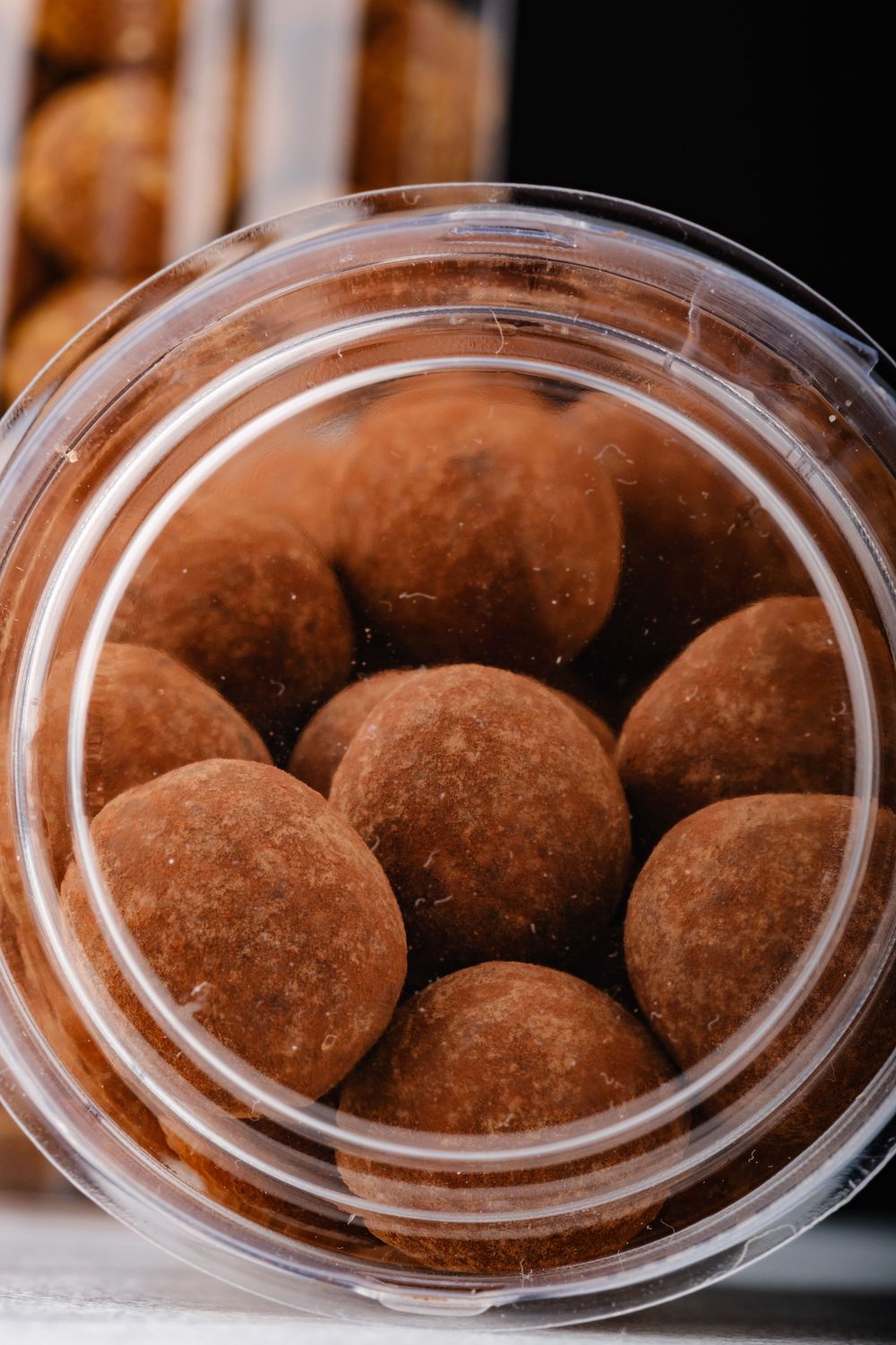 A clear plastic container filled with cocoa-dusted chocolate truffles viewed from above.