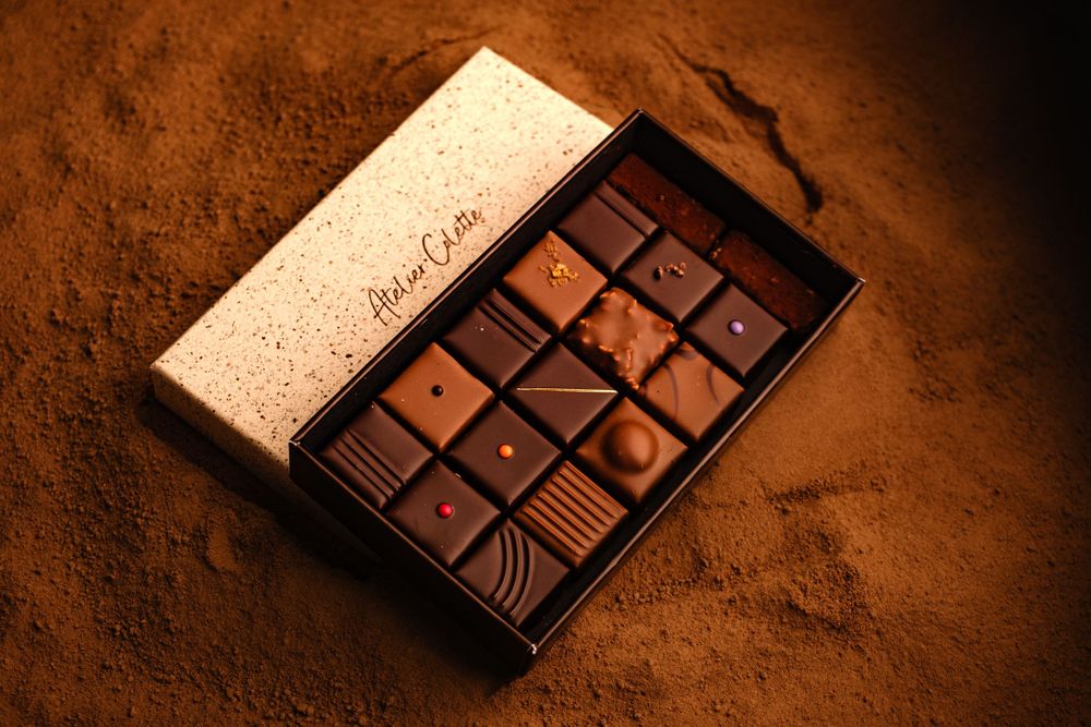 An open box of assorted gourmet chocolates resting on rich cocoa powder.