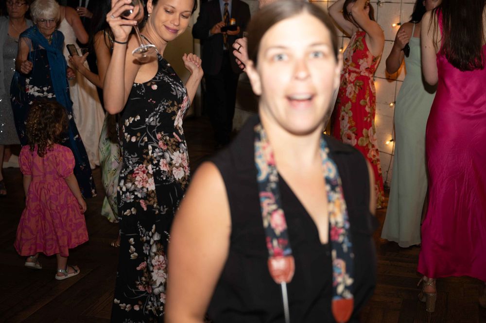 Lively dance party scene with guests celebrating in festive dresses on the dance floor.