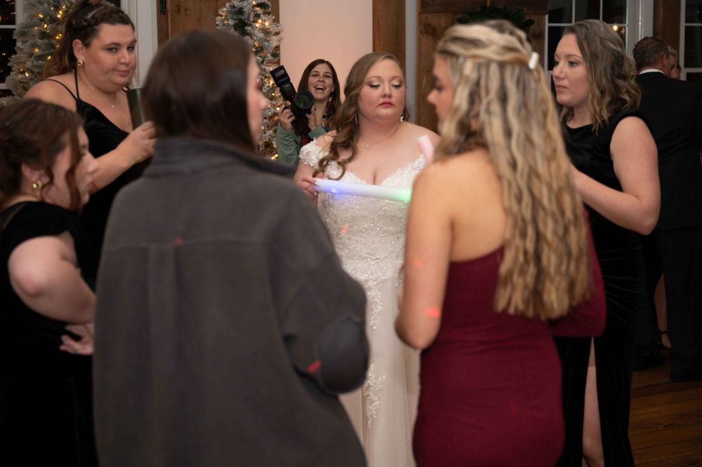 Wedding reception scene with guests gathered in formal attire around bride in white gown.