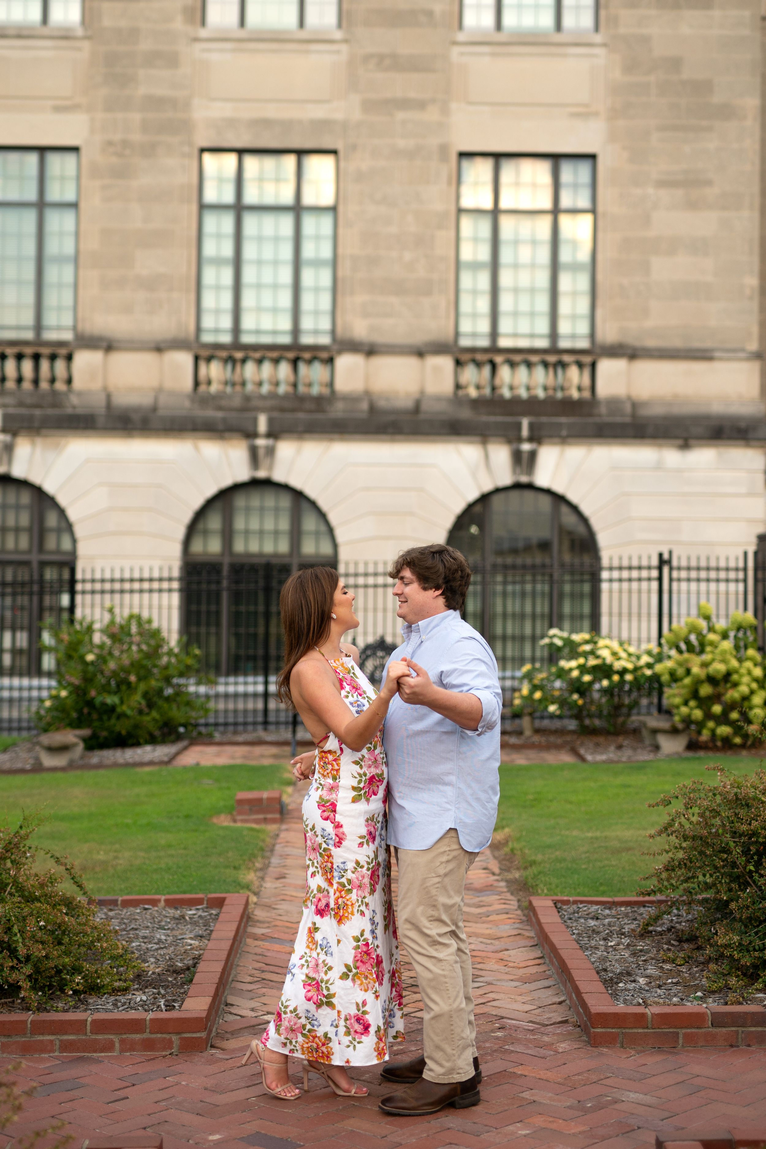 Couple interacting playfully outside a stone building with arched windows.