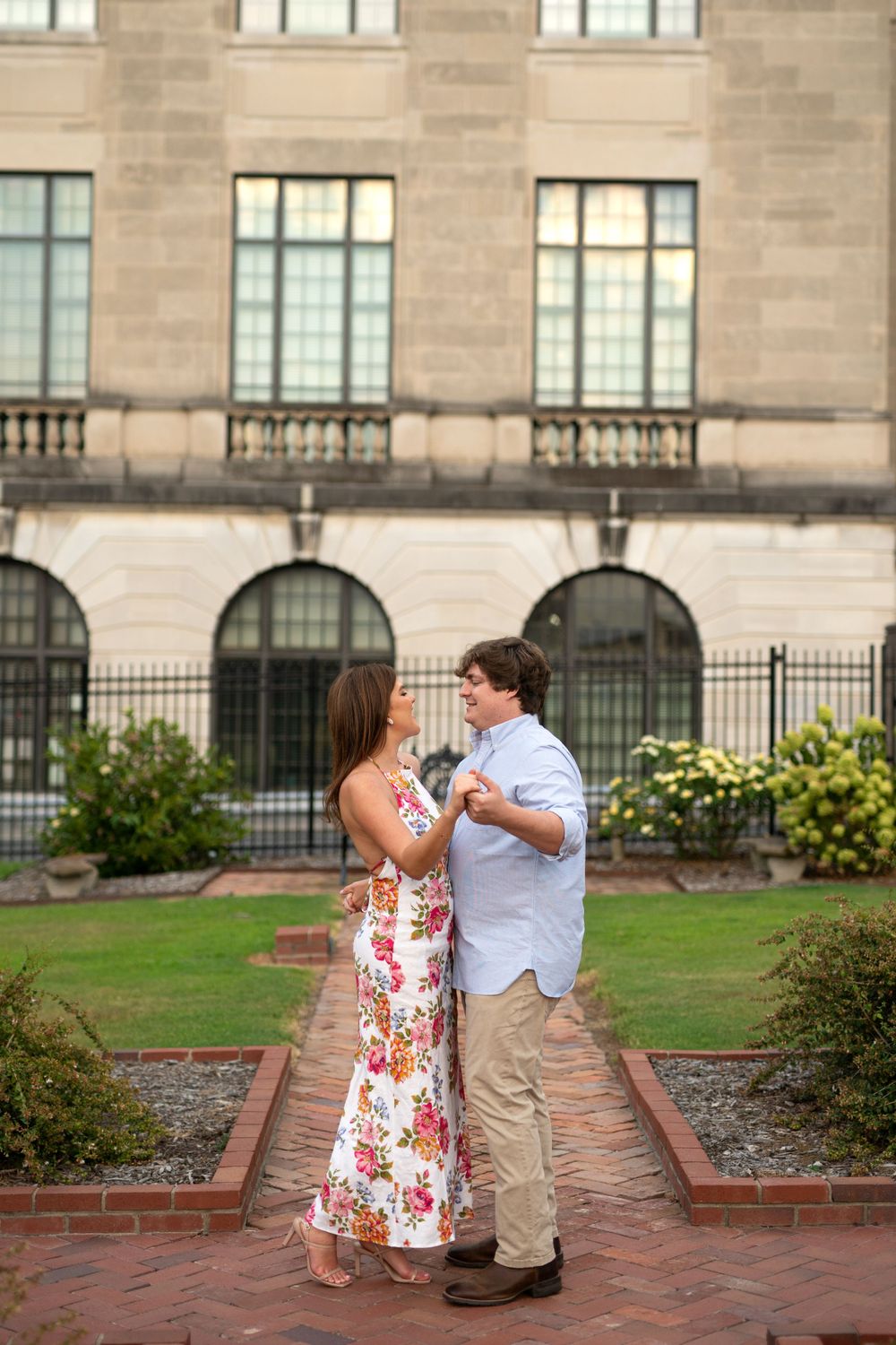 Couple interacting playfully outside a stone building with arched windows.