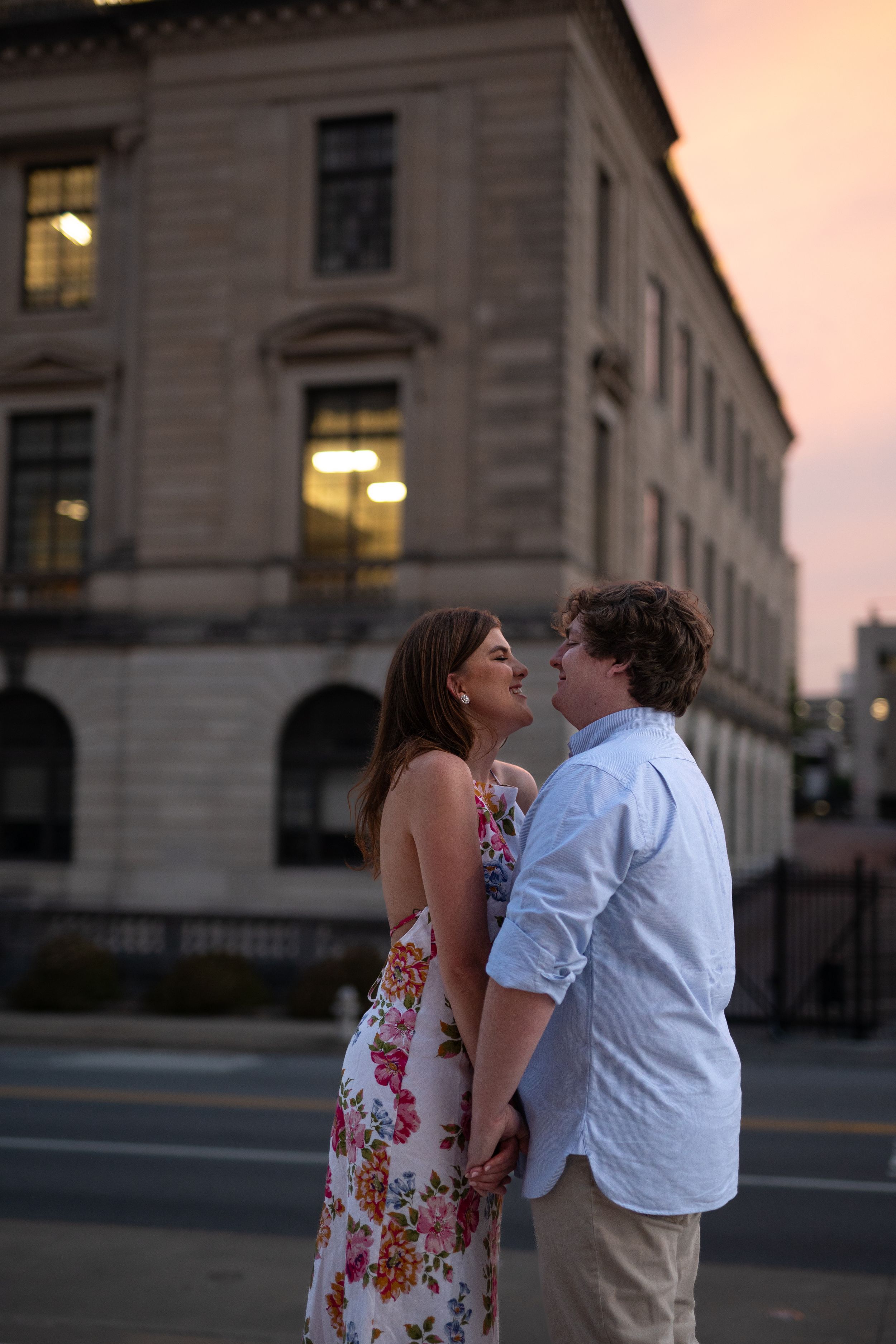 A couple shares a joyful moment outside a historic stone building at sunset.