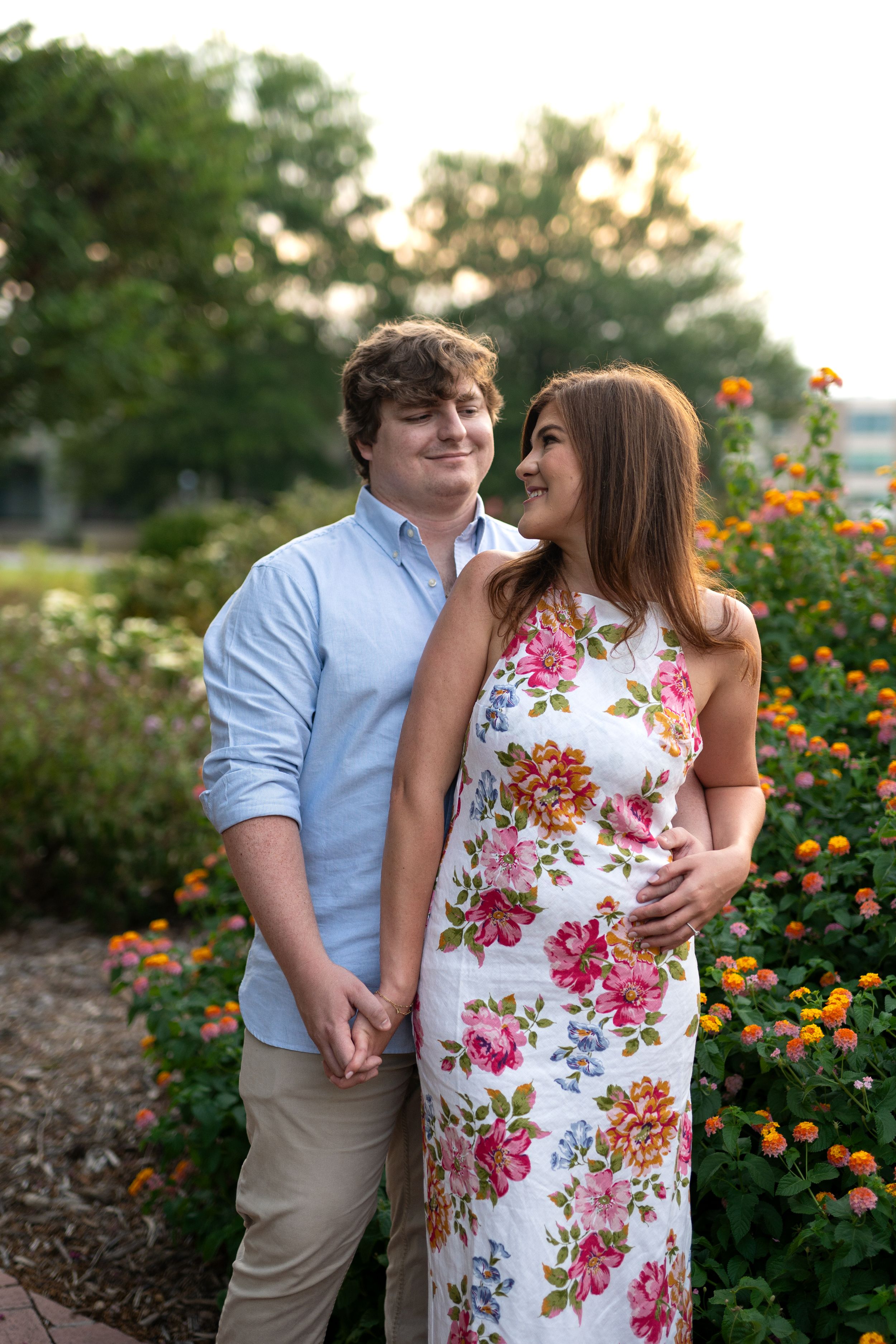 Couple embracing near blooming orange flowers in a garden setting.