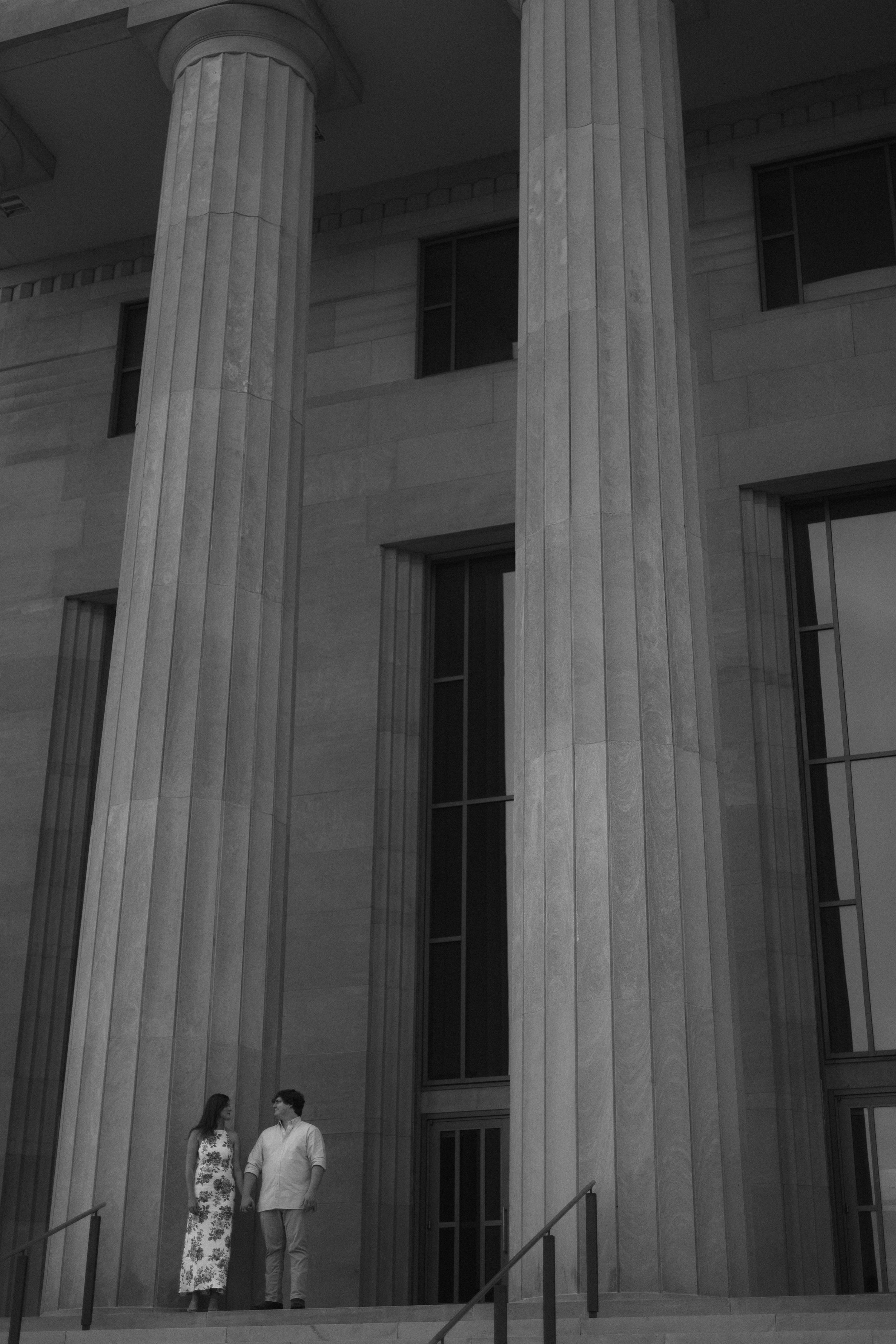 Classical architecture with tall white columns creates a dramatic backdrop for a couple's tender moment.