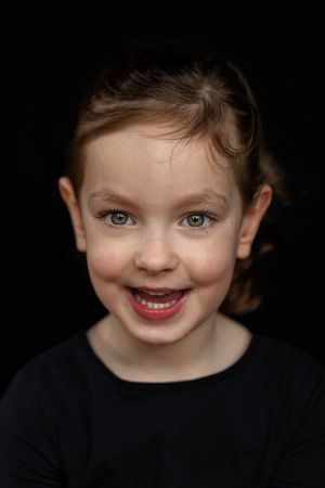 Barbara Kempeneers Fotografie, Kinderportret, Lachend meisje met sprekende ogen en donkerhaar