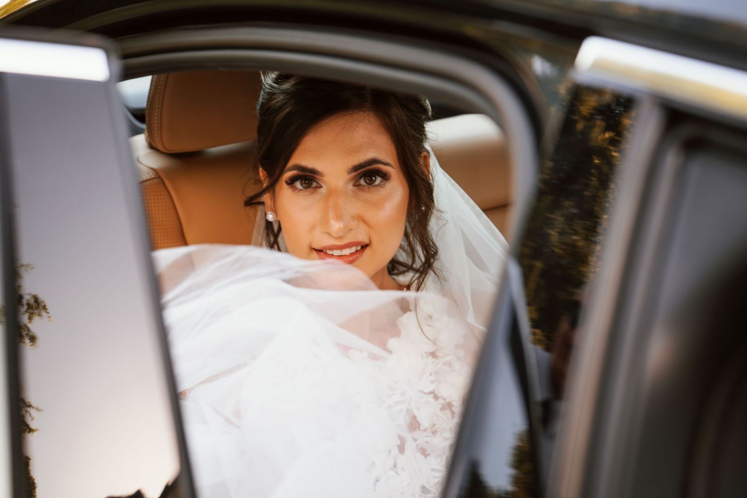 A view through a car window shows someone wearing a white wedding dress.