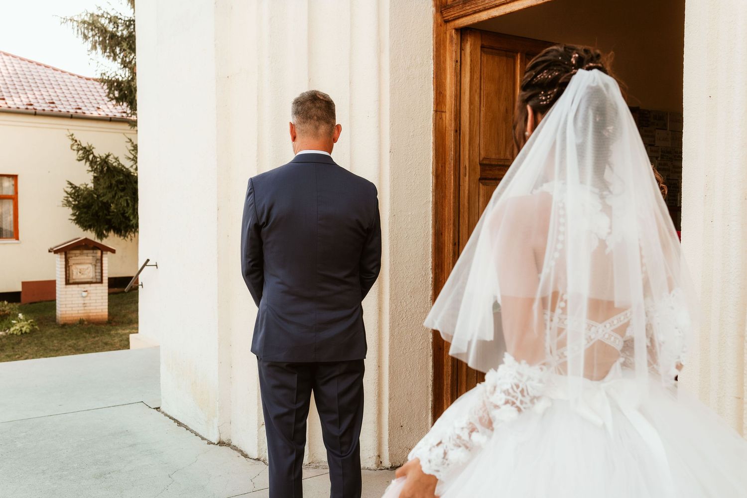 A couple shares a first look moment outside a white church building.