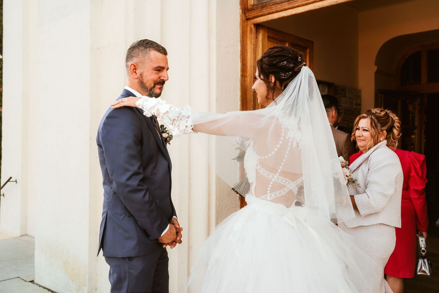 A bride in a flowing white dress reaches out to her groom during their wedding ceremony.