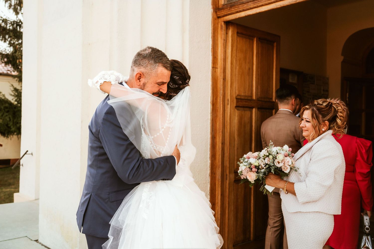 The newlyweds embrace in a heartfelt hug outside a church entrance.
