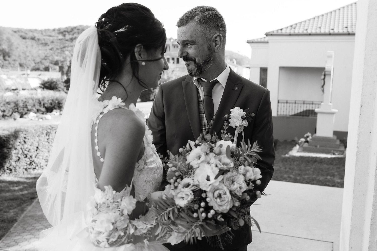 A black and white portrait of newlyweds sharing an intimate moment with a bouquet.