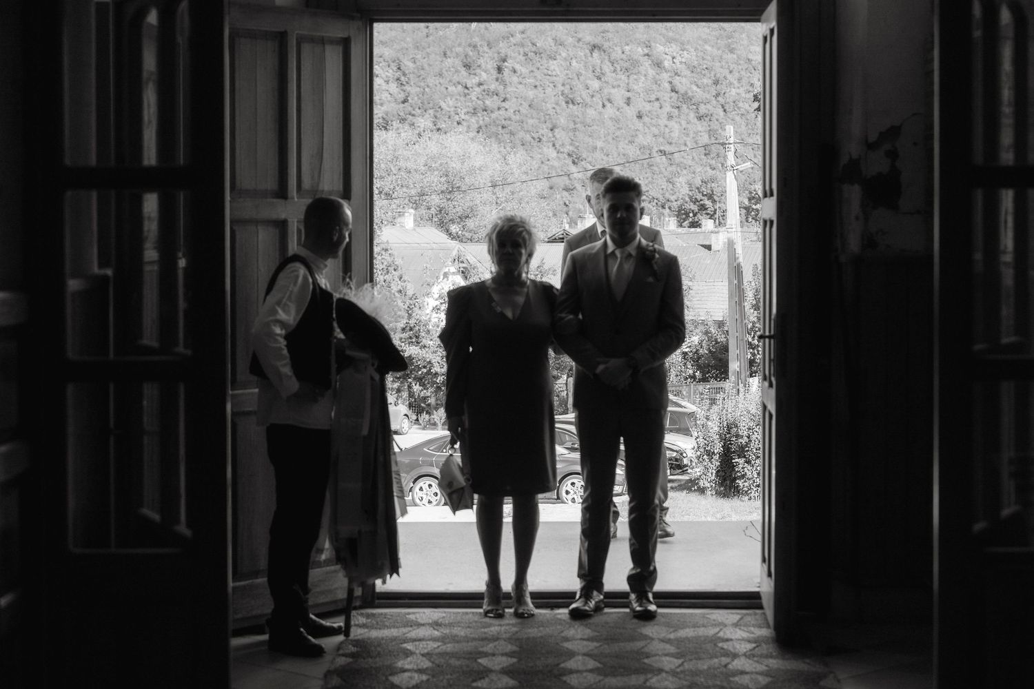 A silhouetted wedding party stands in a doorway creating a dramatic entrance shot.