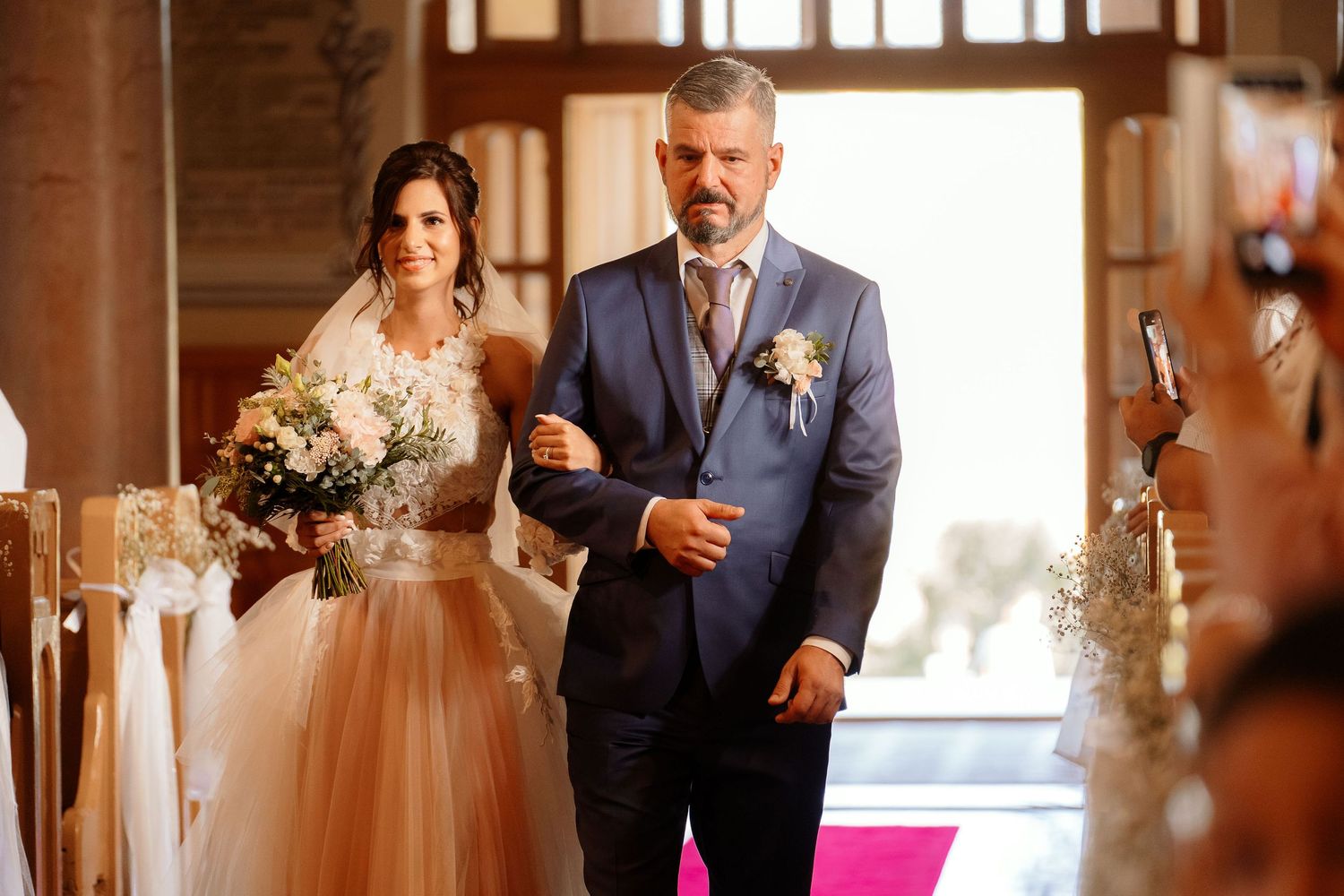 A traditional church wedding processional with the bride in a flowing gown being escorted down the aisle.