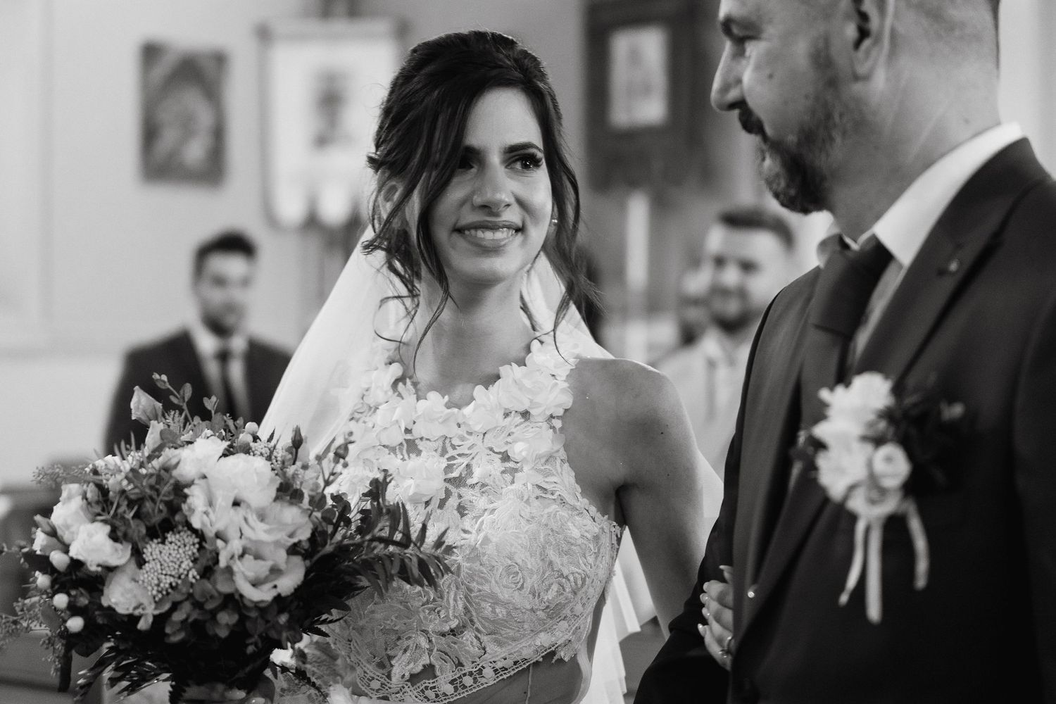 A black and white wedding photo capturing a candid moment during the ceremony.