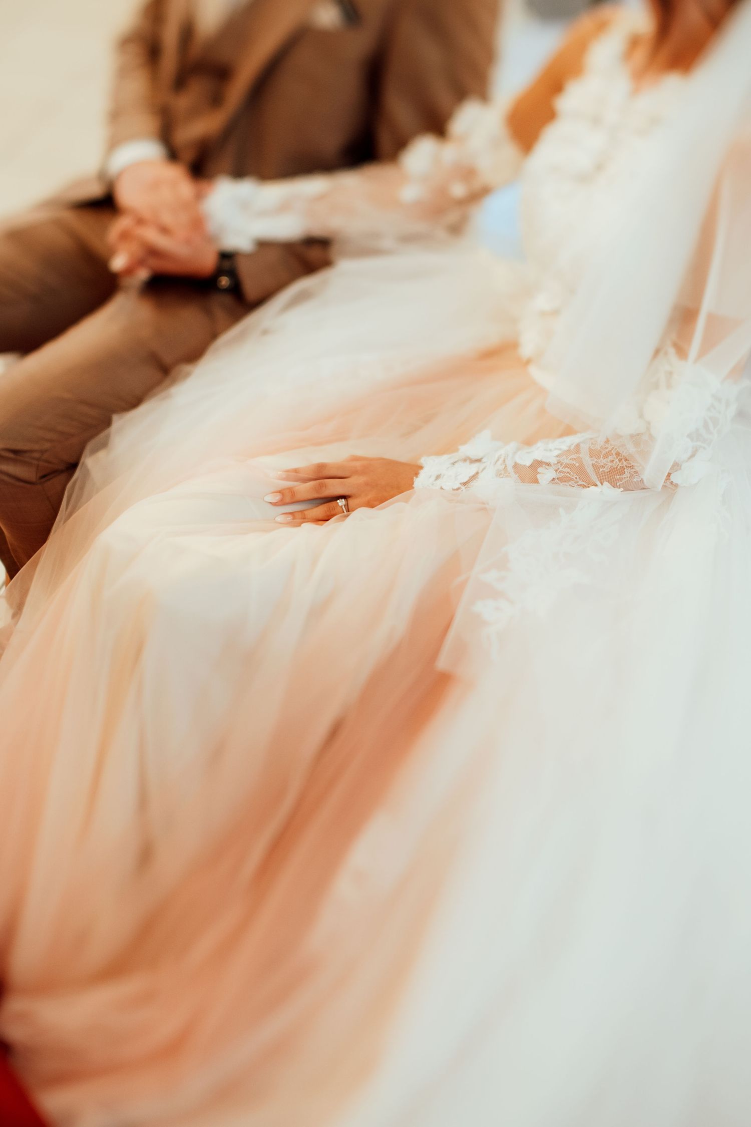 Close-up detail of delicate lace wedding dress fabric and hands.