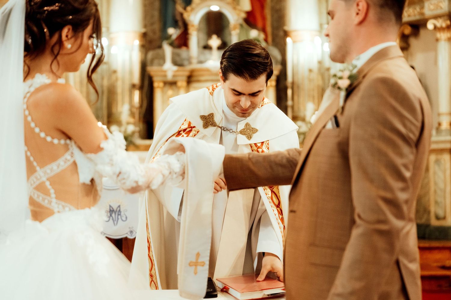 A wedding ceremony in a church with a priest and couple exchanging vows at the altar.