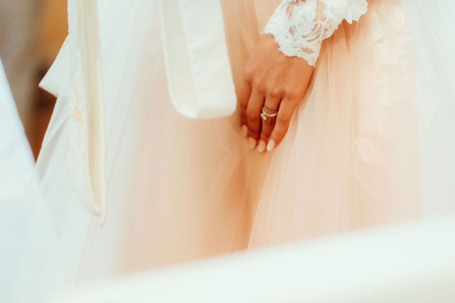 Close-up shot of hands with wedding rings and delicate lace details.