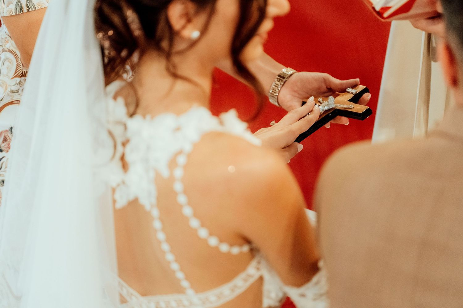 Detail shot of a bride's back featuring pearl strands and lace detailing on her wedding dress.