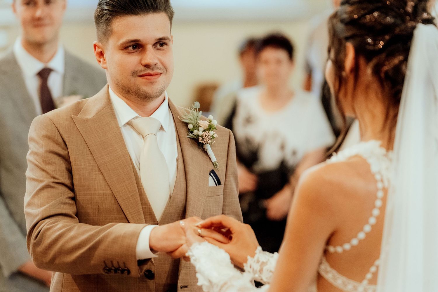 A couple exchanges rings during their wedding ceremony in an elegant church setting.