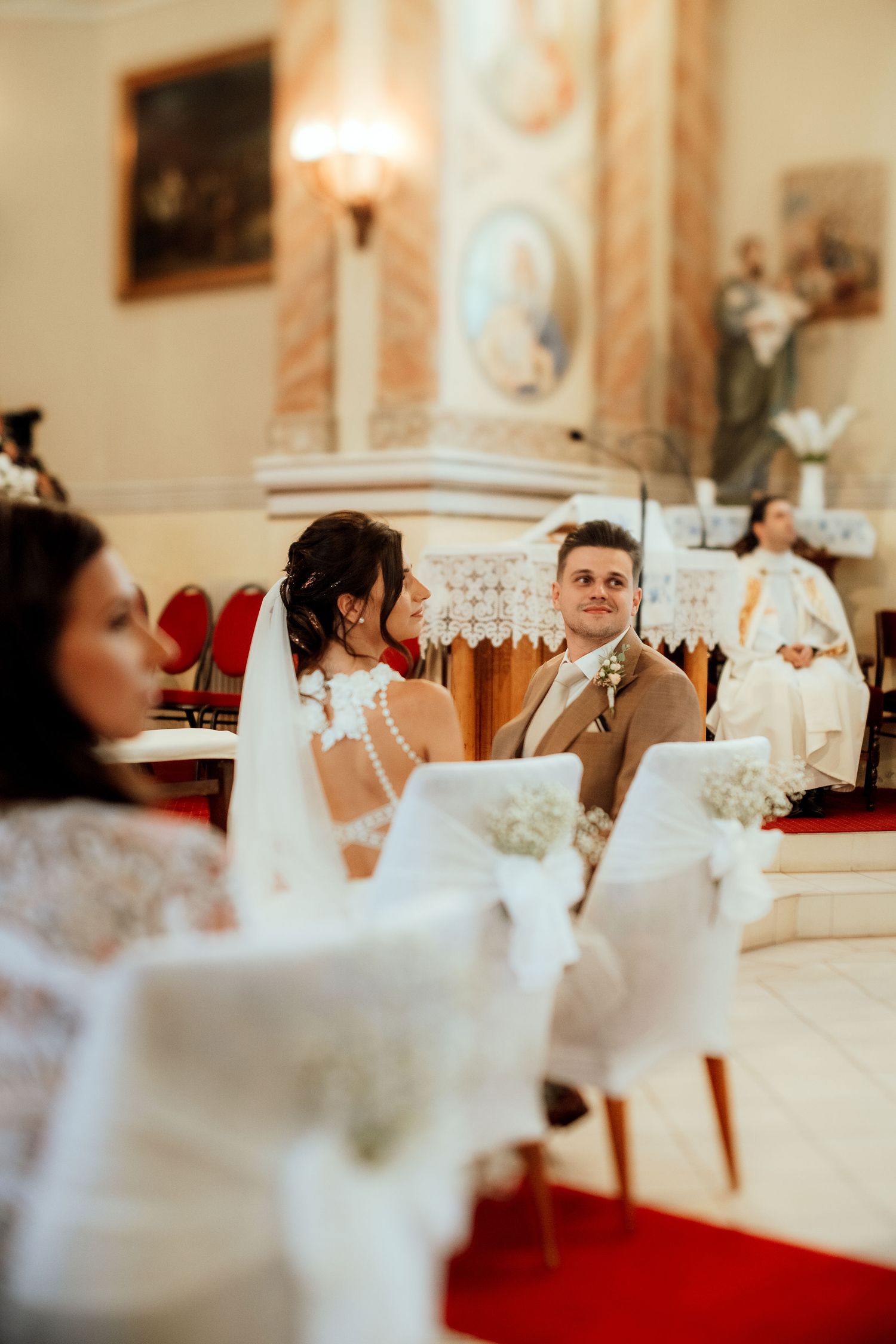 A wedding ceremony in progress inside an ornate church with traditional decorations.