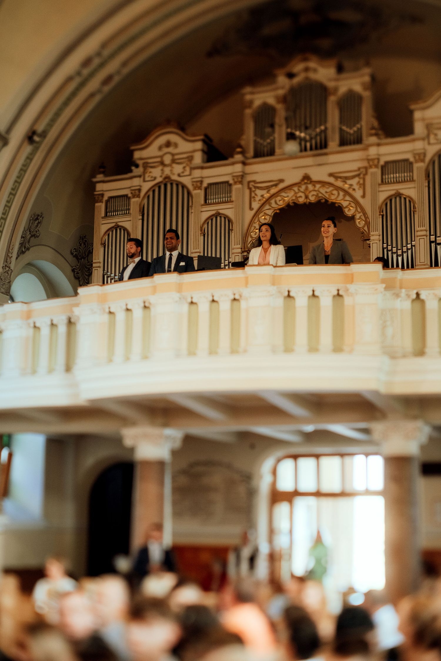 View of a church organ loft with ornate architectural details during a wedding ceremony.