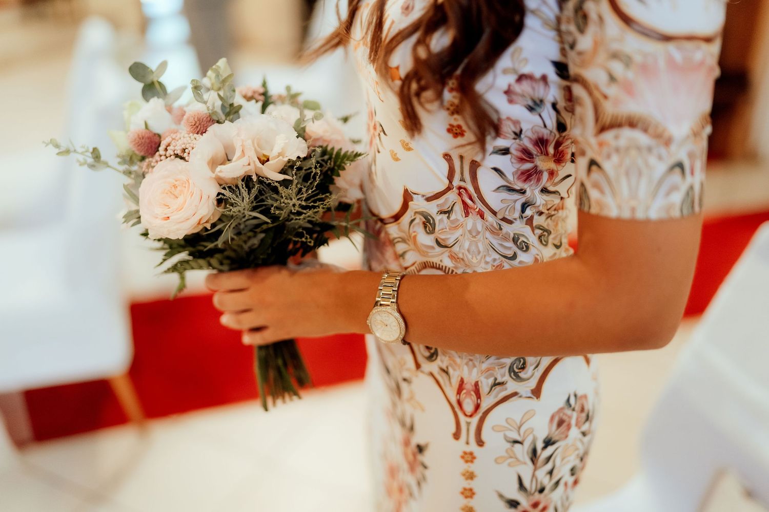 Details of a lace wedding dress and pastel pink bouquet at a church ceremony.