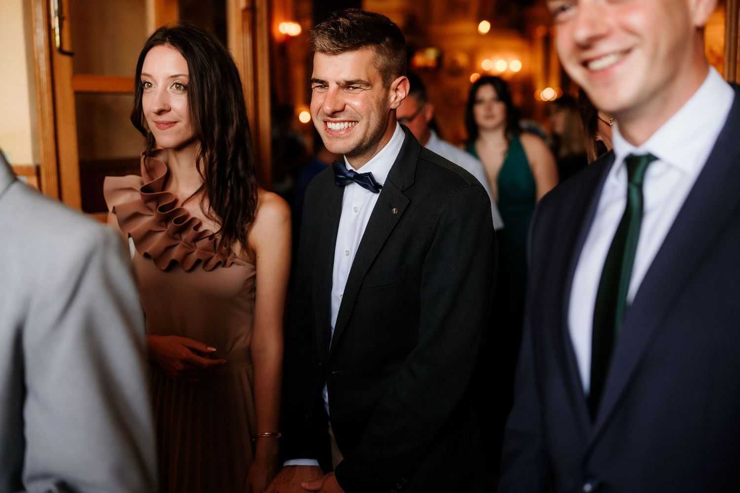 Wedding reception guests socializing in formal attire at an evening event.