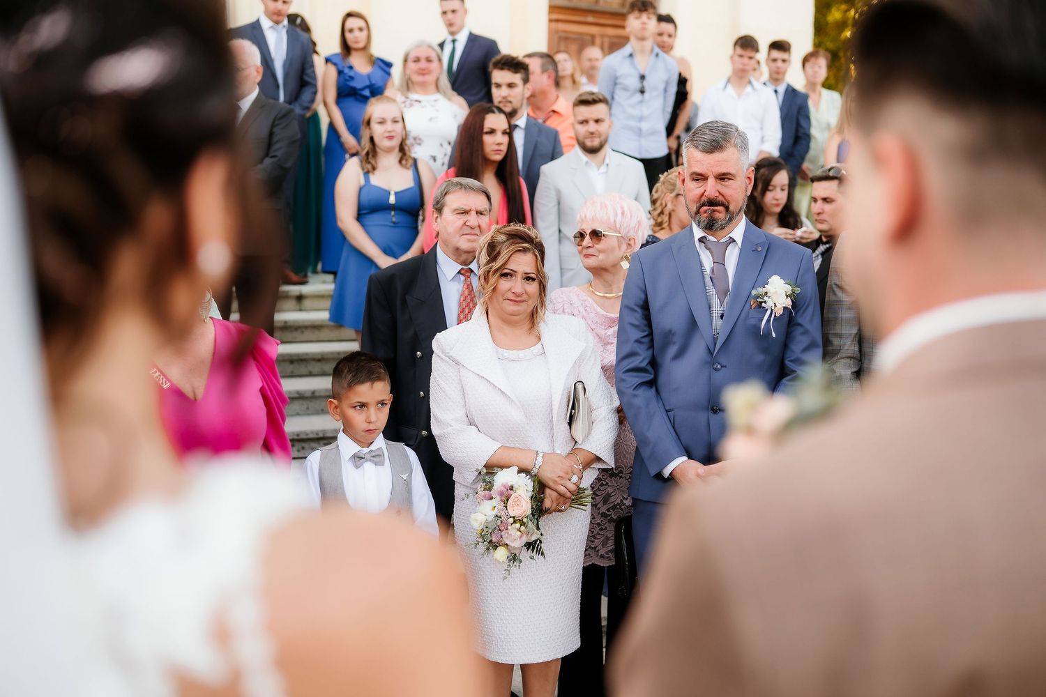 Wedding guests gathered on church steps watching ceremony proceedings.