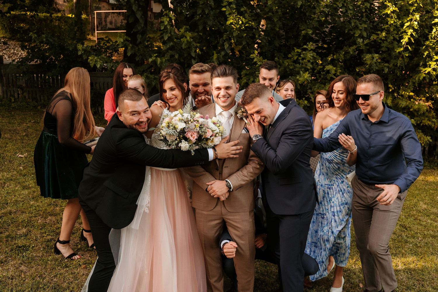 Wedding party members playfully posing together outdoors in formal attire.