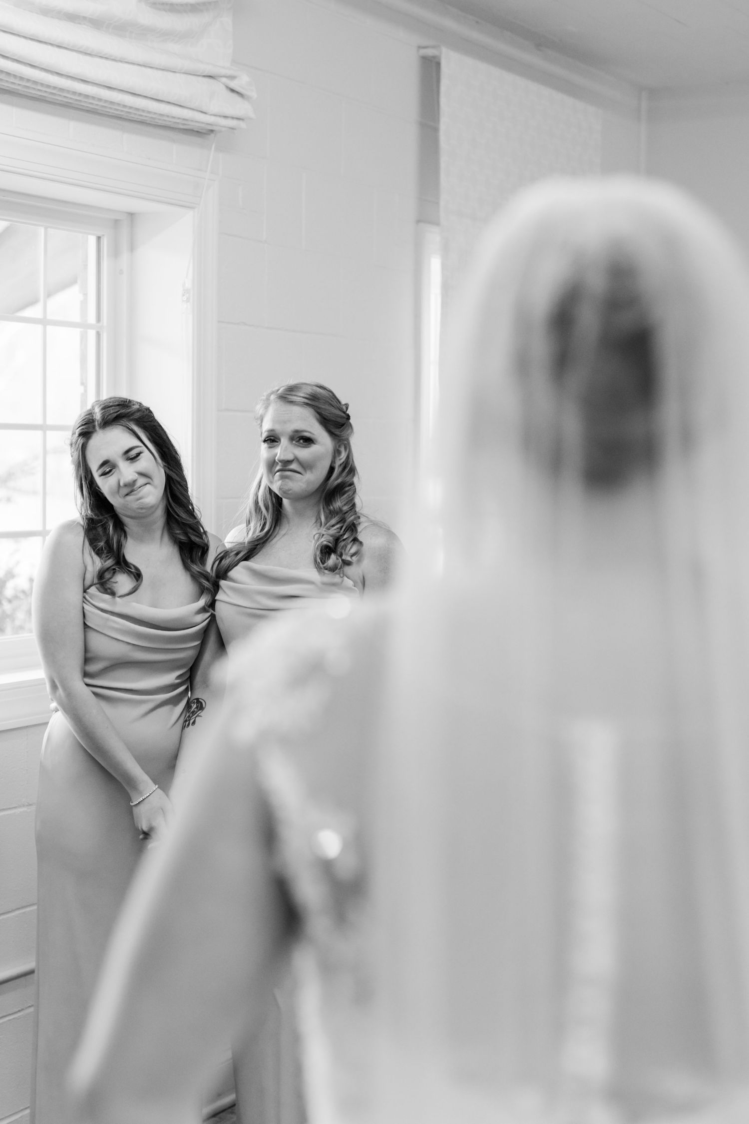 Bridesmaids share emotional embraces in a bright indoor setting before the wedding ceremony.