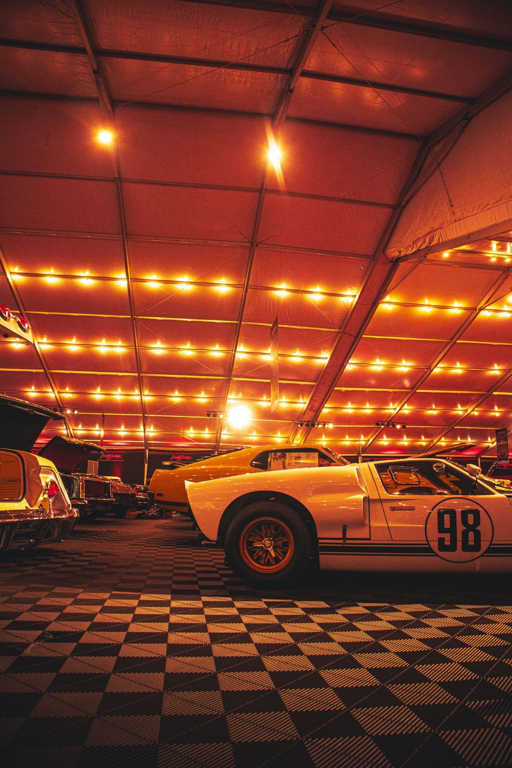 Ford GT40 race car on checkered floor under warm ambient lighting at an indoor car show.