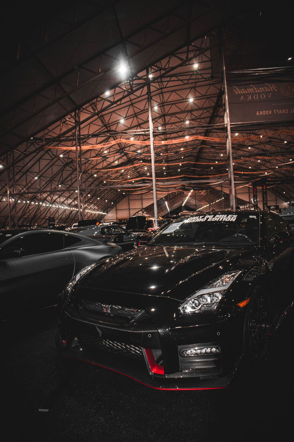 Black Nissan GT-R sports car showcased under dramatic indoor lighting at an automotive exhibition.