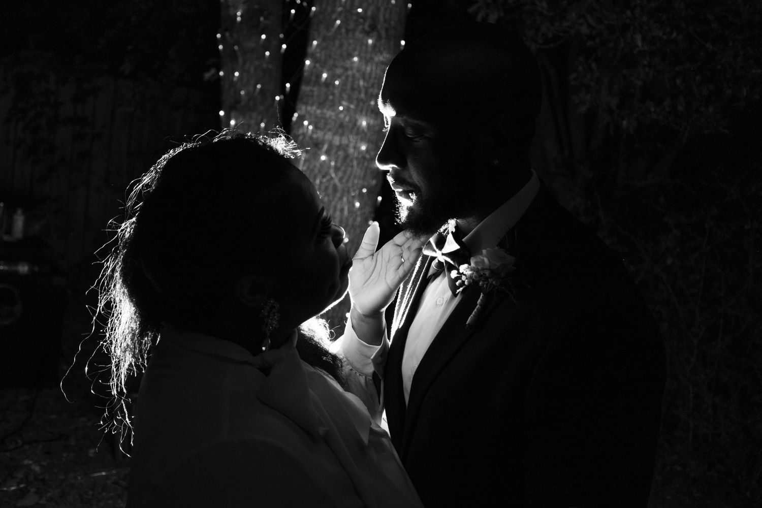 Black and white photo of a romantic couple sharing an intimate moment under sparkling lights.