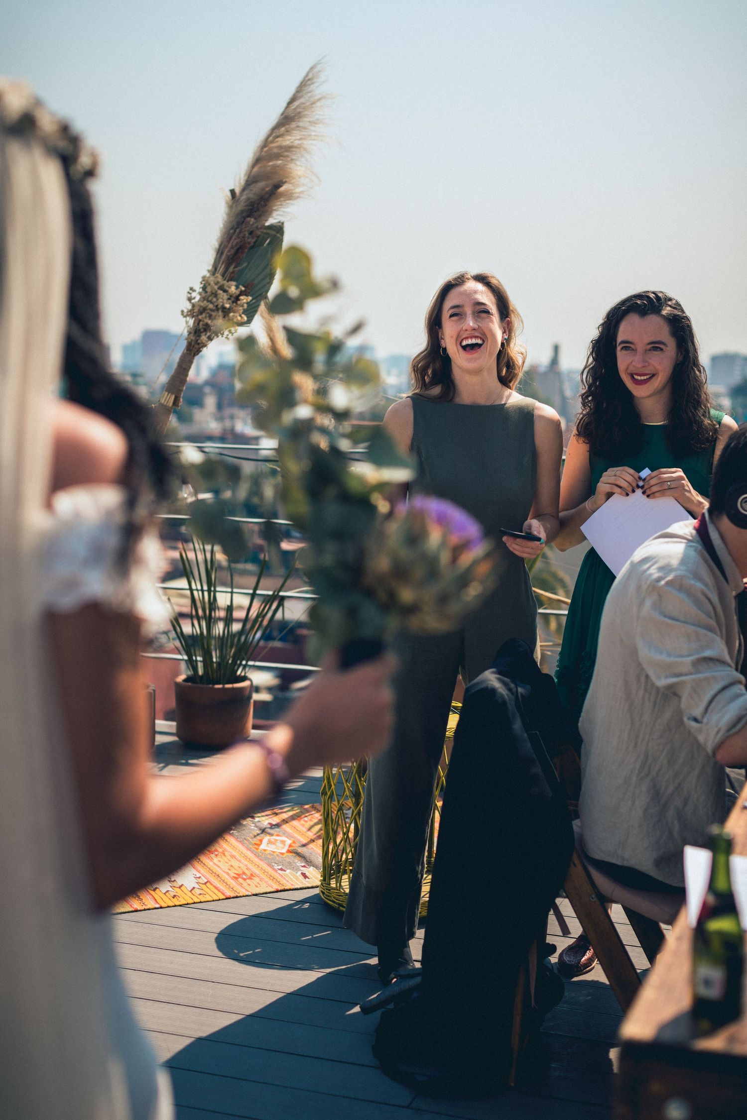 Outdoor gathering on sunny rooftop deck with decorative plants.