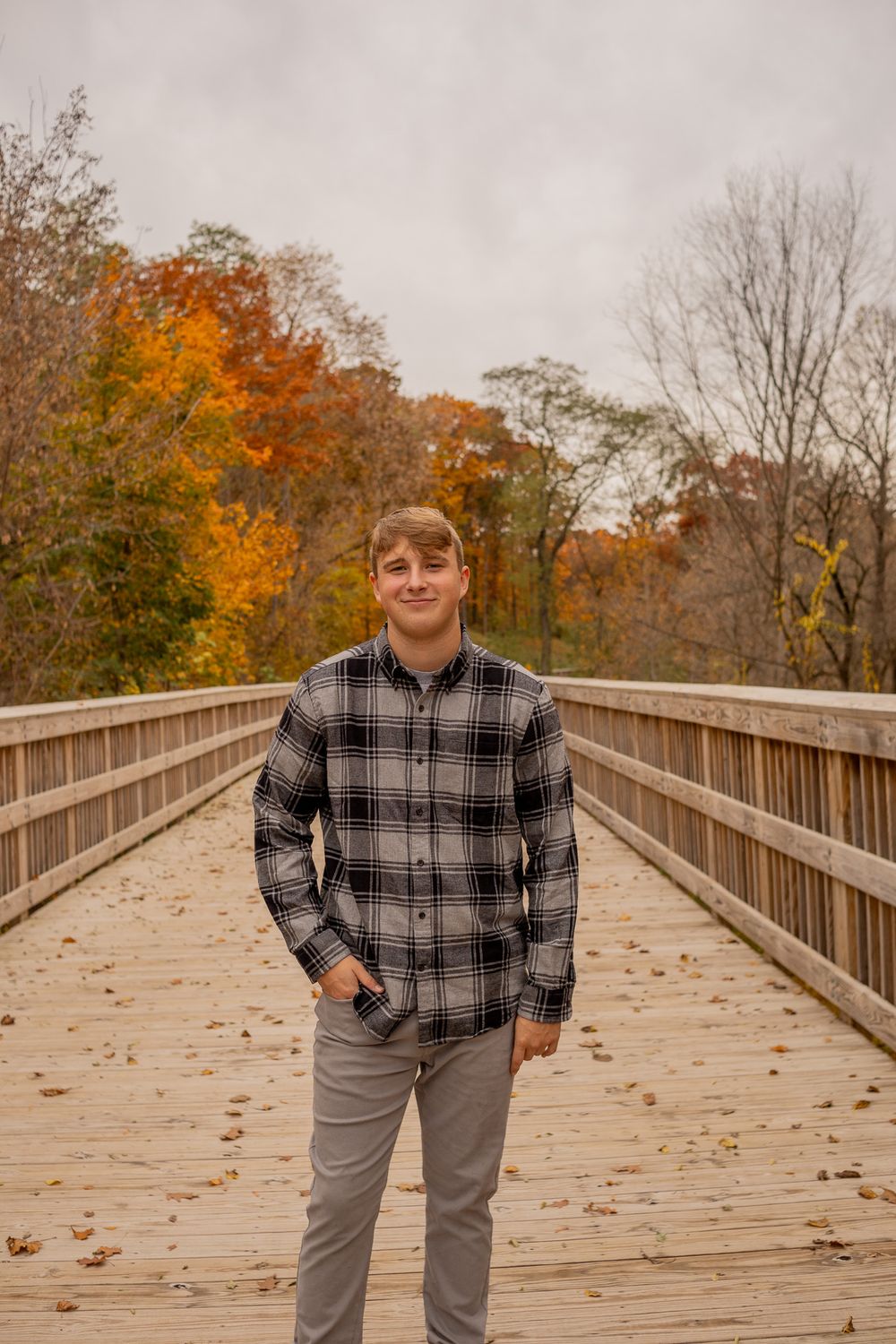 teenage boy standing on bridge with hands in pocket
