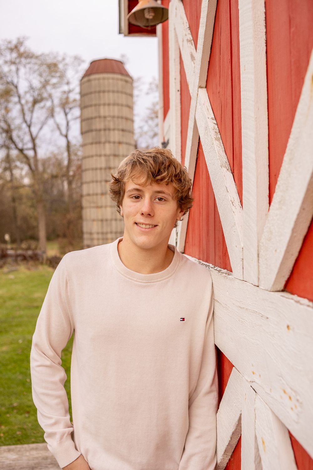 teenage boy leaning against red barn