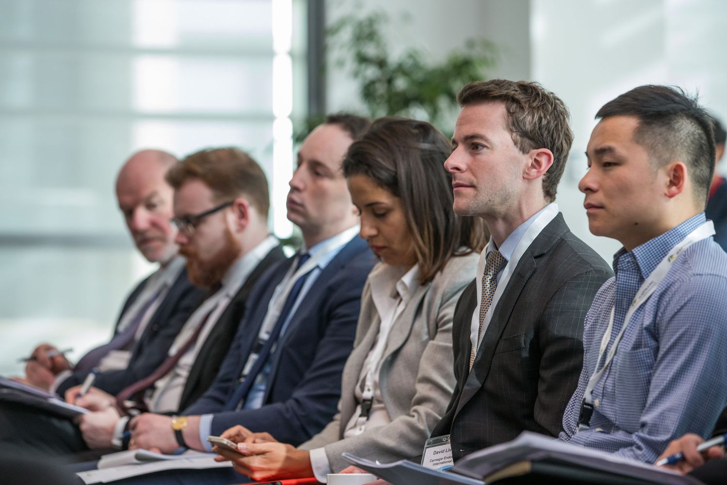 Diverse group of professionals seated in a row at a business conference or seminar.