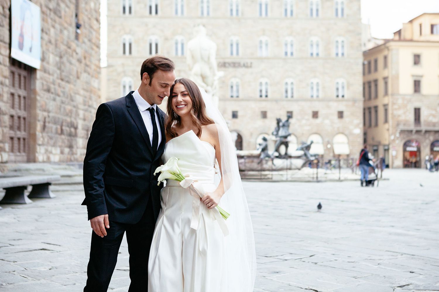bride in a white jumpsuit in groom in a suite from Zara stand outside the Palazzo Vecchio before their elopement wedding
