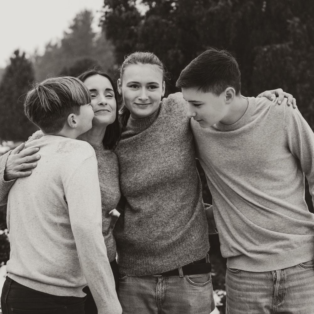 A candid black and white photo of people embracing and laughing together outdoors.