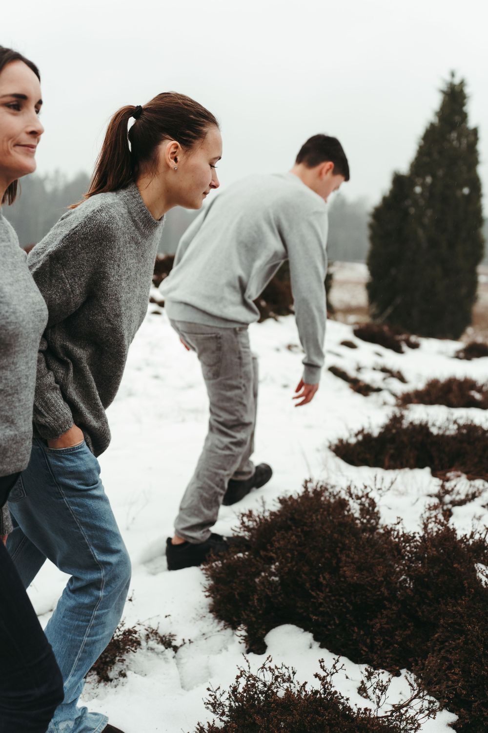 People hiking through a snowy landscape wearing casual winter clothing.