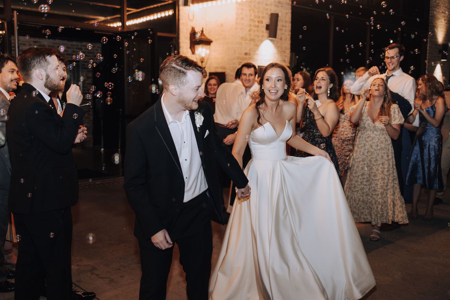 Couple celebrates during their wedding reception as guests cheer in background.