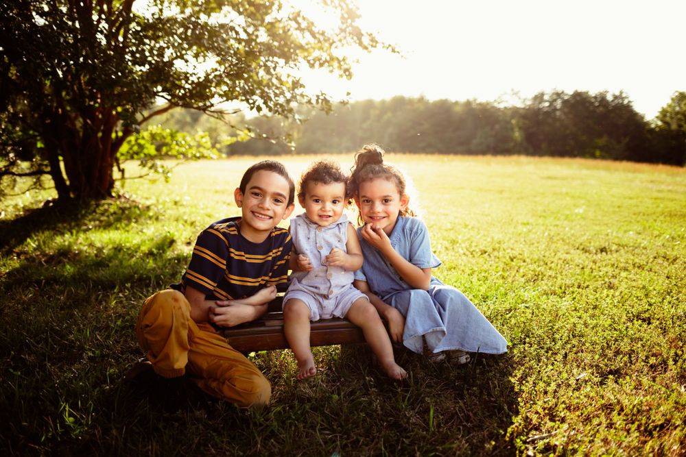 Casual family photo session in a sunny meadow during golden hour.