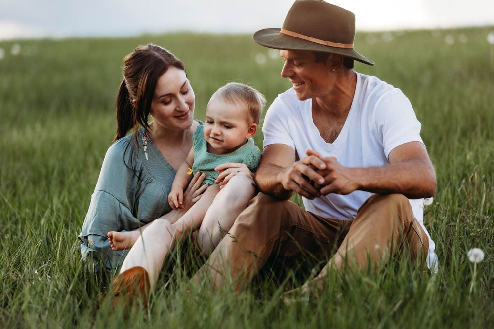 A relaxed family moment in a grassy meadow wearing casual western-inspired attire.