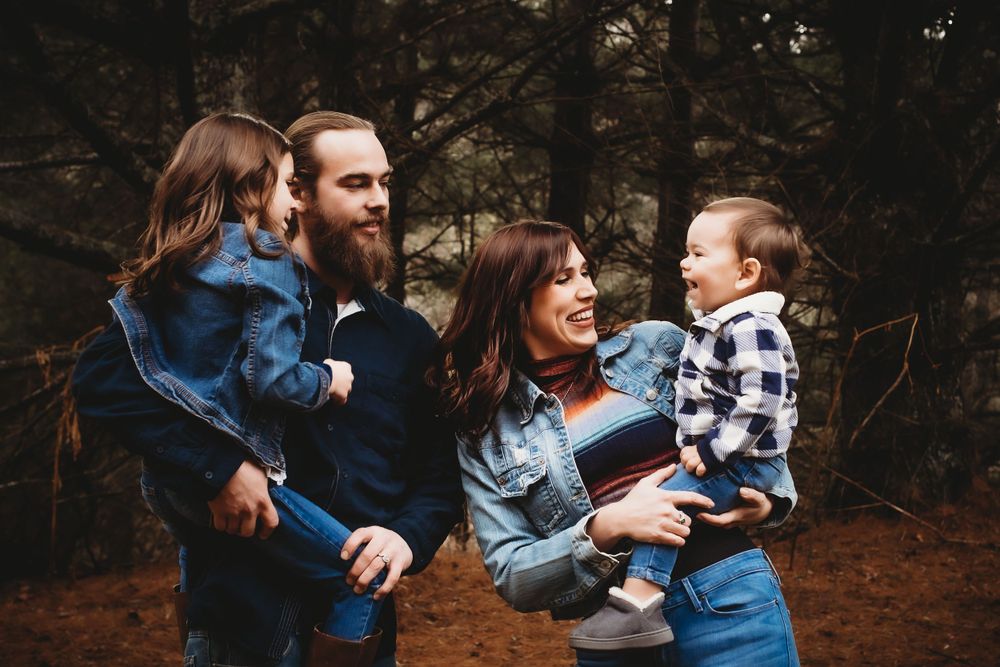Group laughing together while wearing matching denim during an outdoor photo session.
