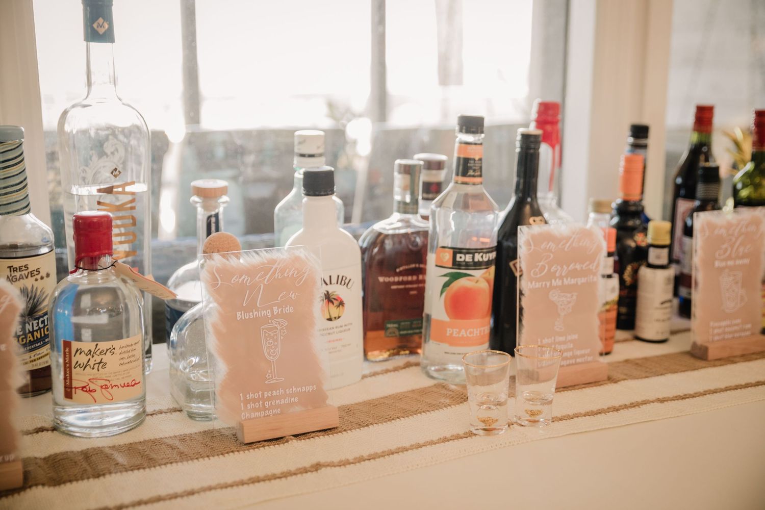A collection of various liquor bottles displayed on a wooden bar shelf.
