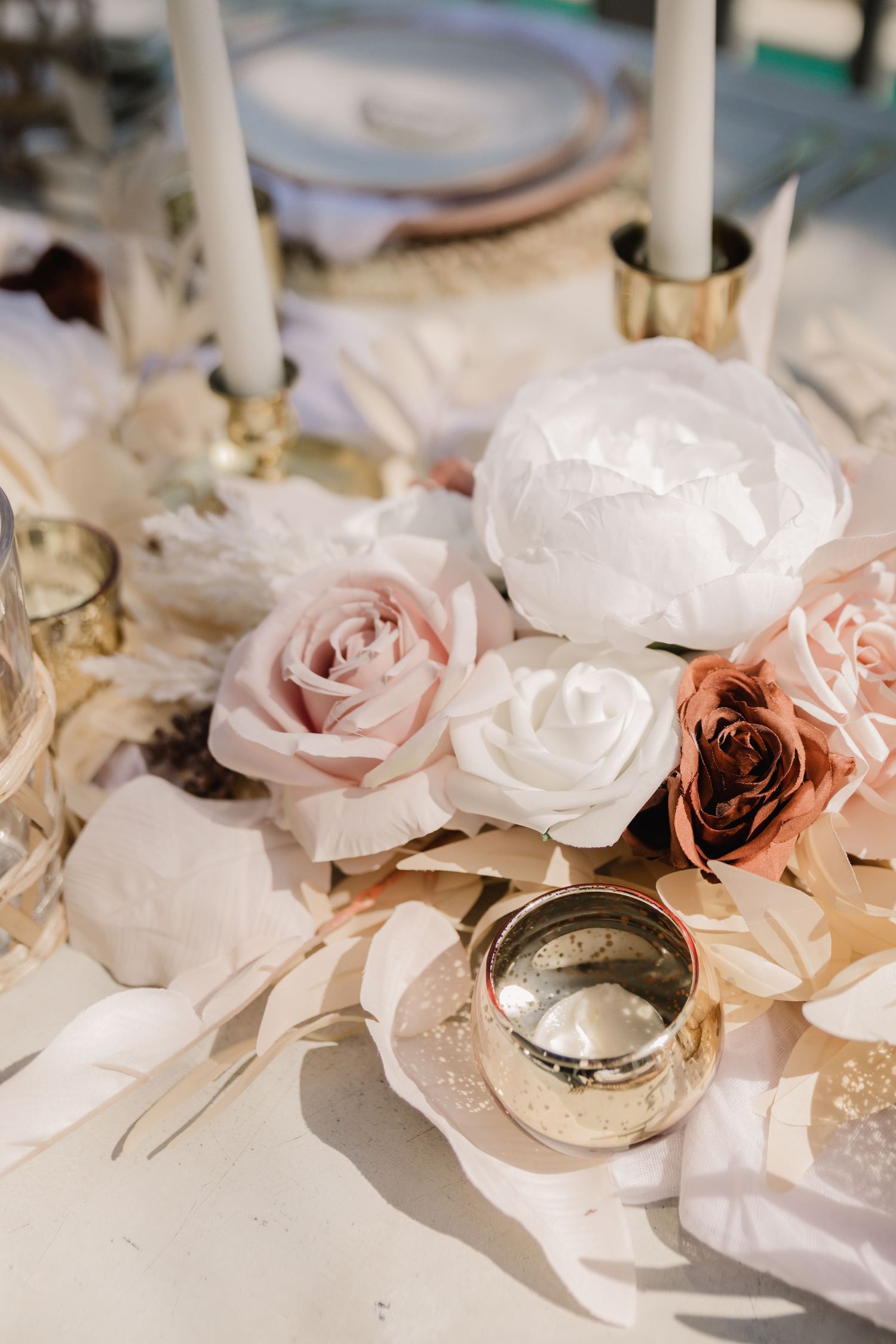 Elegant wedding table decor features soft pink and white roses with gold candleholders.