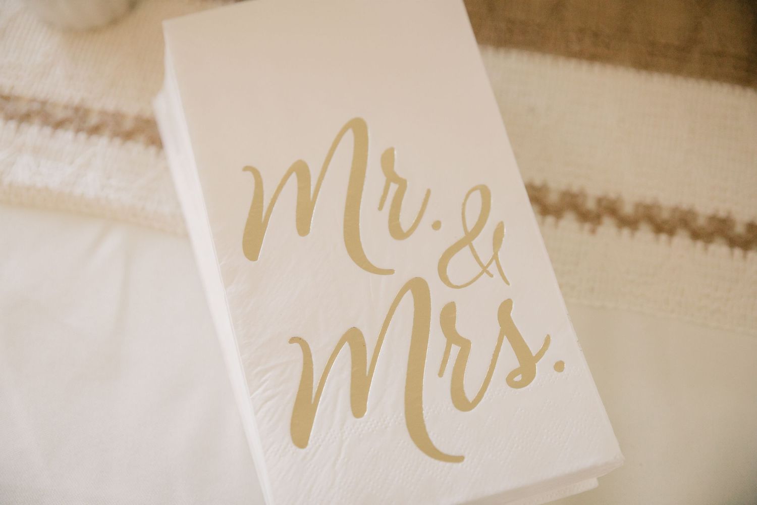 Wedding stationery with gold calligraphy reading Mr. & Mrs. on white paper.